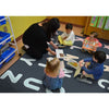 Teacher and children sitting on a classroom rug with educational materials