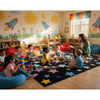 A colorful classroom rug with a black star-pattern while a teacher reads to her students