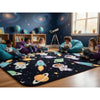 A children's space-themed area rug with colorful astronaut and rocket illustrations on a dark blue background, shown in a decorated kids' room with children sitting on bean bags and reading.