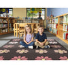 Two children sitting on a rug with flower pattern rug in a library setting.