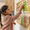 Child playing with a wooden wall puzzle on a wall