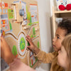 Children playing with a wooden educational toy featuring a cityscape and road.