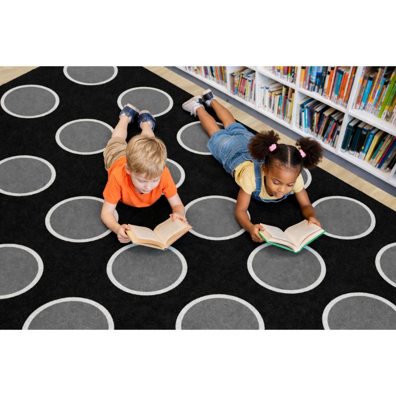 Two children reading books on a black circular patterned rug in a library. Night Clouds by SensoyrEdge