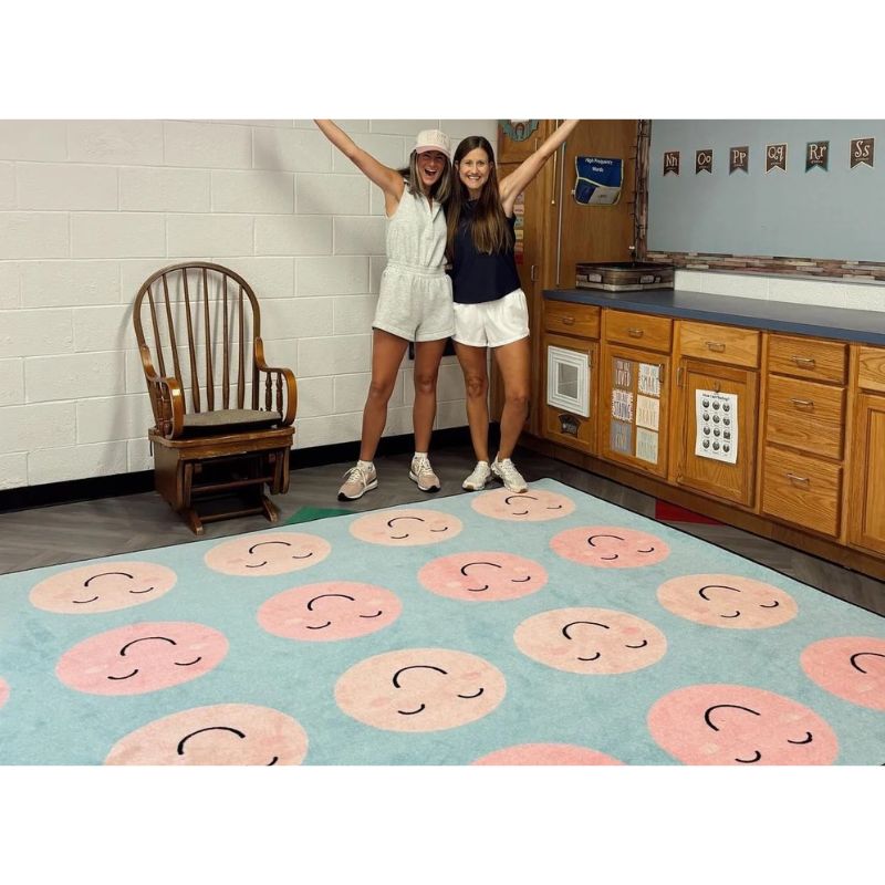 Two teachers standing on a SensoryEdge rug with pink and black designs in a school room.