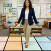 Teacher standing on a SensoryEdge classroom carpet with educational materials and decorations on the walls.