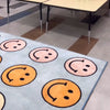 Colorful smiley face rug on a checkered floor with tables in the background