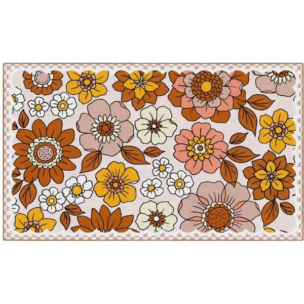 A rectangular area rug with a retro 1970s floral pattern featuring large stylized flowers in orange, yellow, pink, and white with brown leaves on a cream background, finished with a brown checkered border.