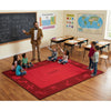 Teacher with students on a red math-themed rug in a classroom.