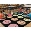 Children sitting on a rug with smiley face patterns in a classroom setting.