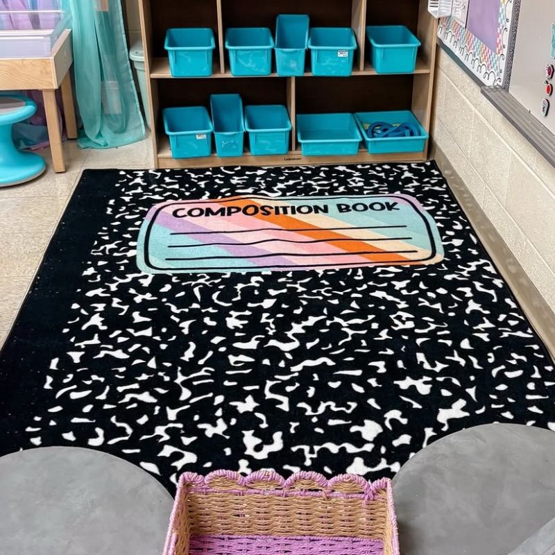 Classroom setting with a black and white patterned rug featuring a colorful 'composition book' design.