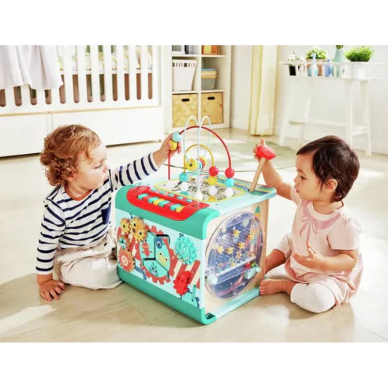 Two children playing with a colorful activity cube in a room.