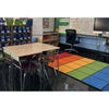 Classroom with colorful rug, desks, and chairs.